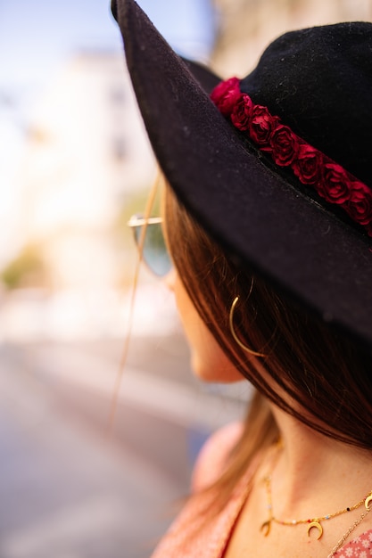 Outdoor close up portrait of beautiful young woman wearing blue cat eye sunglasses and hat posing in the city street. Female spring fashion .