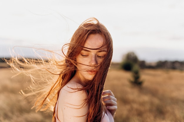 Outdoor close up portrait of ginger cute girl with freckles on sunset 