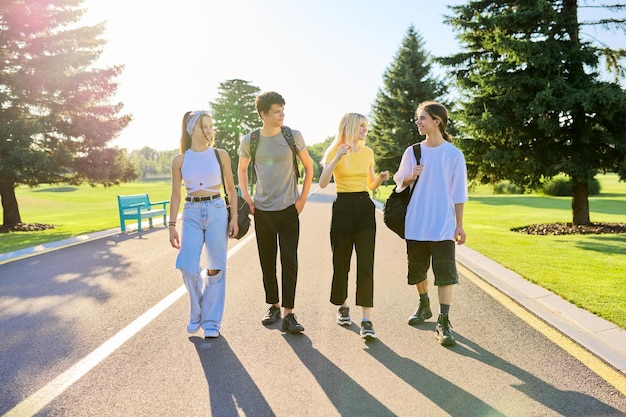 Outdoor four teenagers walking together on road