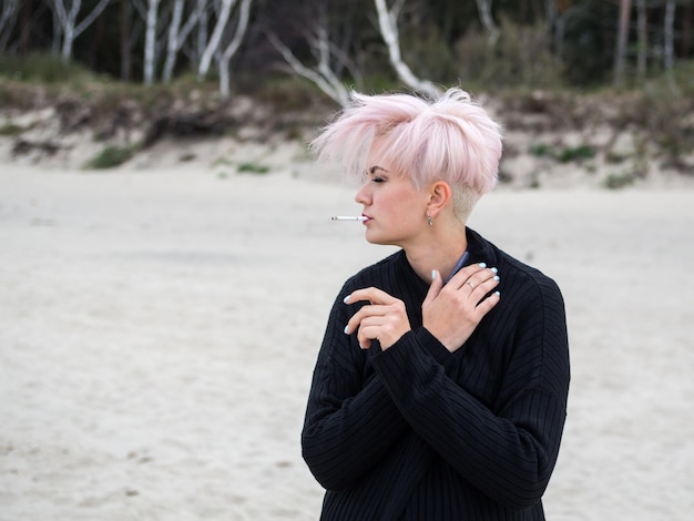 Outdoor lifestyle fashion portrait of amazing sexy young smoking woman with stylish trendy haircut