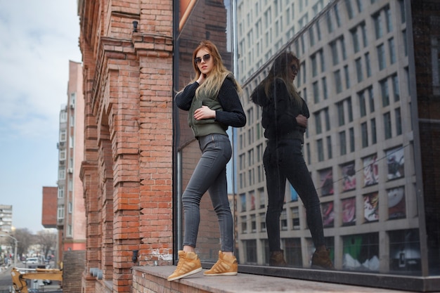 Outdoor lifestyle portrait of pretty young girl, wearing in hipster swag grunge style on urban background