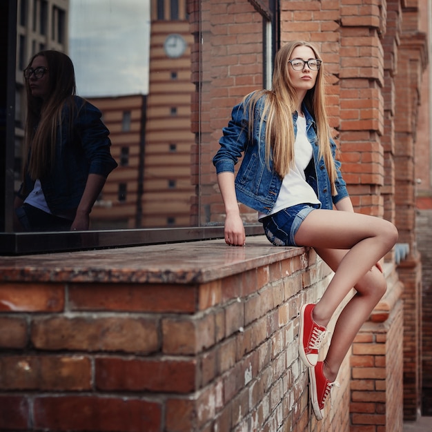 Outdoor lifestyle portrait of pretty young girl, wearing in hipster swag grunge style on urban background