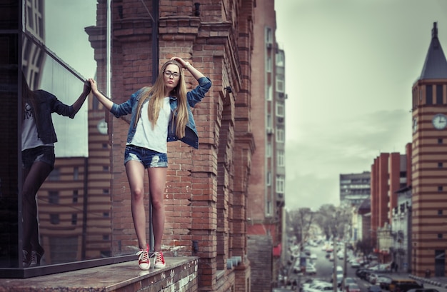 Outdoor lifestyle portrait of pretty young girl, wearing in hipster swag grunge style on urban background