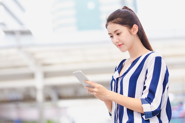 Outdoor lifestyle young businesswoman looking on smartphone