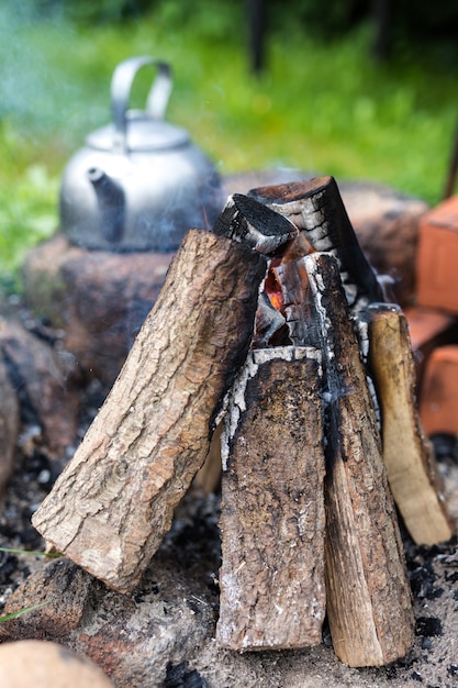 Outdoor picnic kettle with a vintage touch near a bonfire.