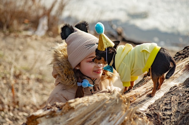 Outdoor portrait of 10- 11 year old girl wearing warm beige jacket with a chihuahua dog. birthday