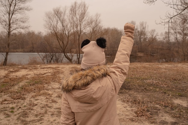 Outdoor portrait of adorable 10- 11 year old girl wearing warm jacket. A schoolgirl in a beige hat.