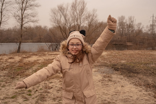 Outdoor portrait of adorable 10- 11 year old girl wearing warm jacket. A schoolgirl in a beige hat.