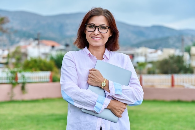 Outdoor portrait of a confident positive woman with a laptop in her hands