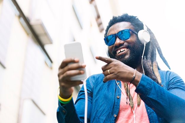 Outdoor Portrait Of Handsome African Young Man Listening Music.