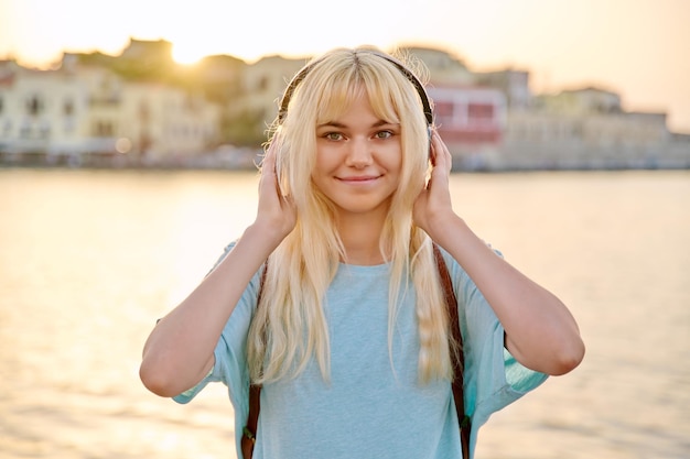 Outdoor portrait of happy young blonde woman wearing headphones