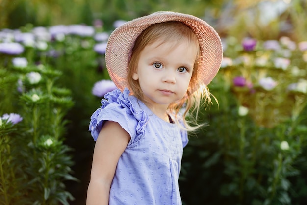 Outdoor portrait. Little toddler lovely girl with flowers at beautiful garden. child outdoors in nature