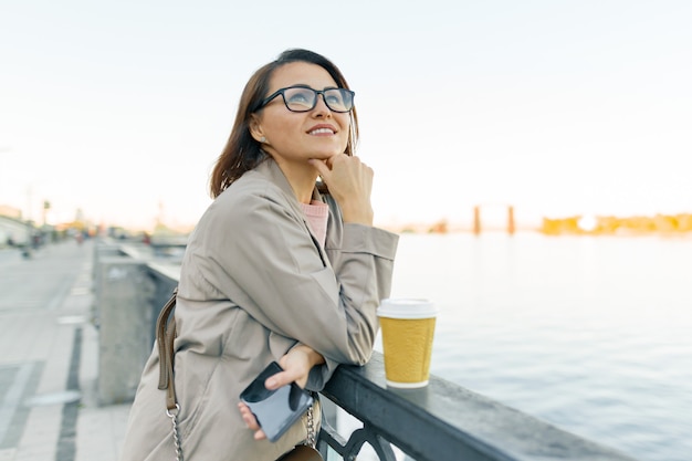 Outdoor portrait of mature smiling woman in glasses