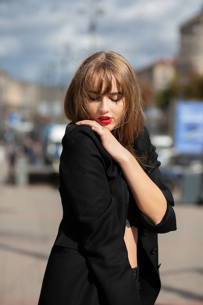 Outdoor portrait of sensual brunette woman wears black suit walking at the avenue