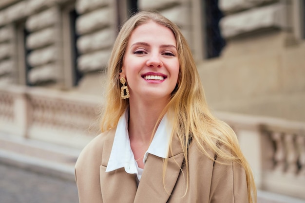 Outdoor portrait of young beautiful fashionable woman wearing trendy jacket with small shoulder bag, walking in street of european Chezh Praha city.