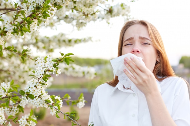 Outdoor shot of displeased Caucasian woman feels allergy