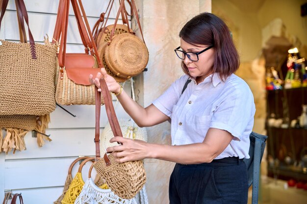 Outdoor showcase with woven knitted bags woman shopper choosing a bag