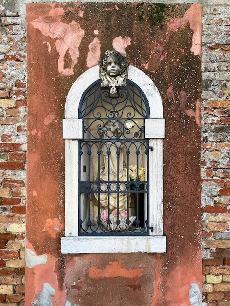 Outdoor statue of Madonna behind bars in wall