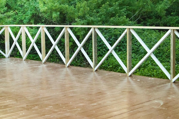 Outdoor summer terrace with brown wooden floor and railings in the form of a lattice