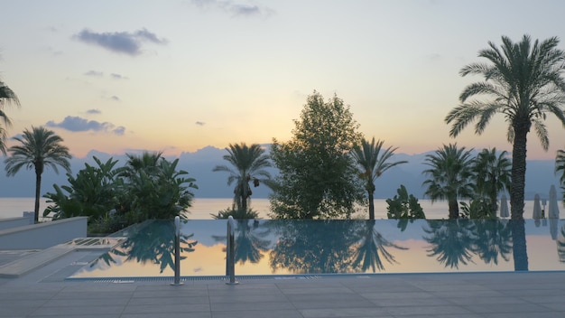 Outdoor swimming pool on resort scene with nature background at sunset