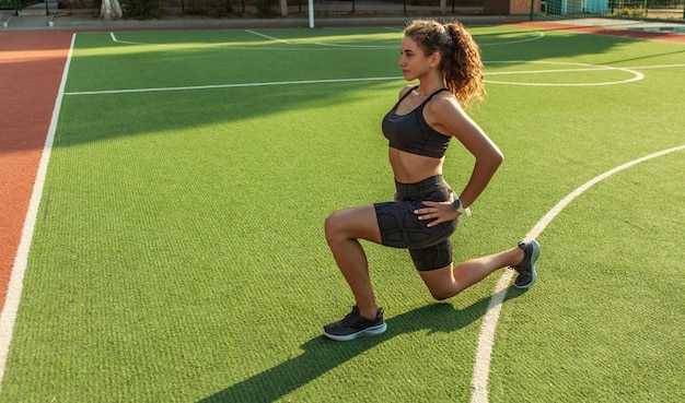 Outdoor training. Attractive sexy fitness model warms up and stretches the muscles before training