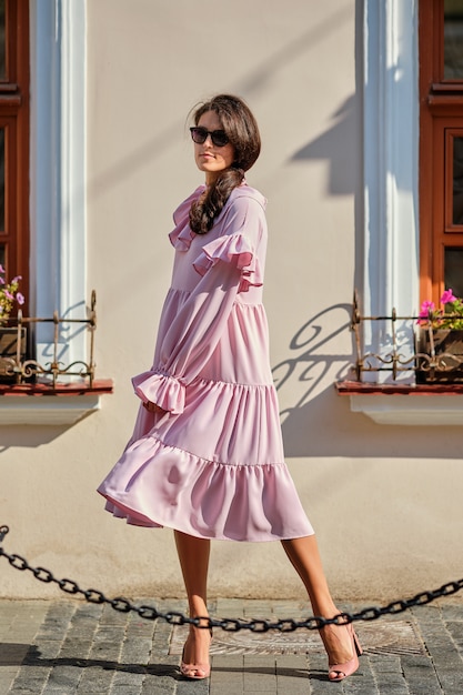 Outdoor urban portrait of young beautiful stylish girl in oversized pink dress