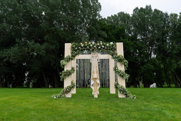 Outdoor wedding of a park A beautiful dress is hanging on the wedding arch Front view