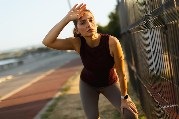 Outdoor workout at sunset with woman catching her breath along a scenic jogging path