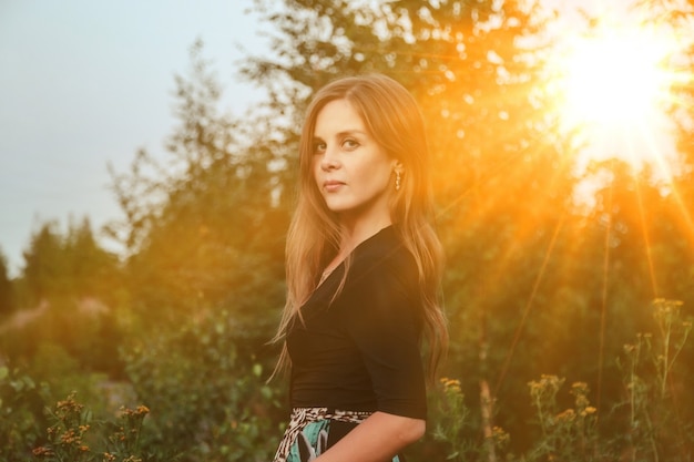 Outdoors portrait adult woman on nature walking in summer forest of dusk. Dreamer lady in wear walk evening on parkland. Positive emotion of female on park at dawn