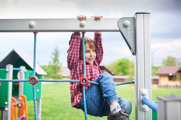 Photo outdoors portrait of cute preschool boy at the playground on natural green