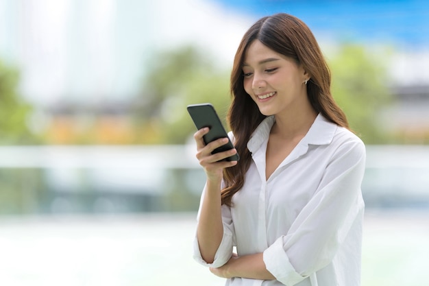 Outdoors portrait of Happy young woman using a phone in the city