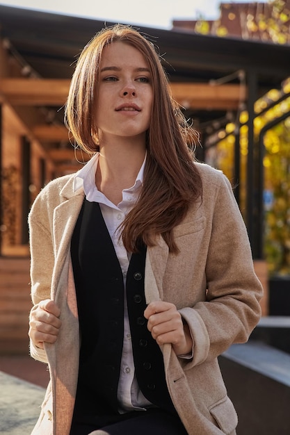 Outdoors portrait of young caucasian red headed girl in coat with long hair