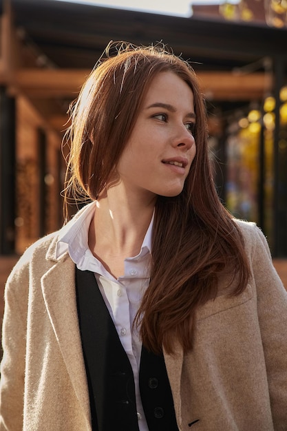 Outdoors portrait of young caucasian red headed girl in coat with long hair