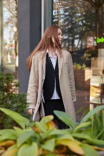 Outdoors portrait of young caucasian red headed girl in coat with long hair