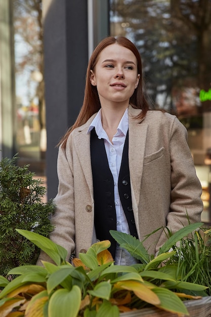 Outdoors portrait of young caucasian red headed girl in coat with long hair