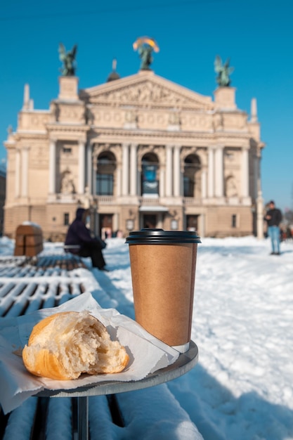 Outdoors table with bench coffee to go and croissant