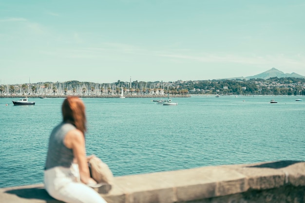 Outoffocus woman observing a bay with seafaring ships