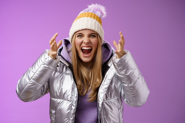 Outraged fed up pissed blond woman screaming out loud hateful bending forward shaking hands disrespect angry arguing heartbroken cry standing bothered quarreling, purple background.