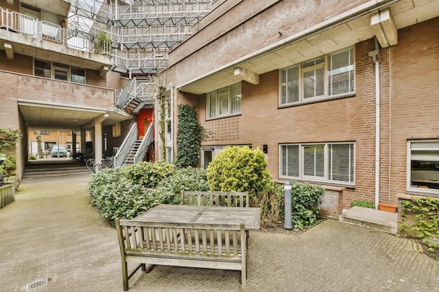 An outside area with a wooden bench and fire escape stairs in the building is bricked up to the second floor