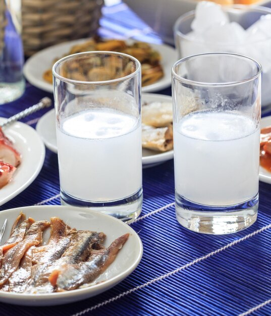 Ouzo raki alcohol with ice cubes next to seafood meze