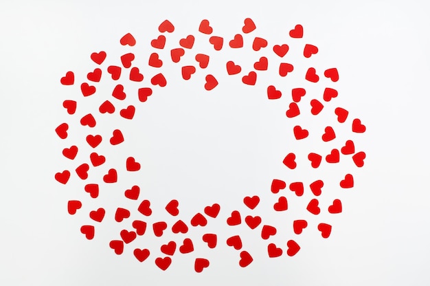 Oval frame of red paper hearts on a white background with space for text