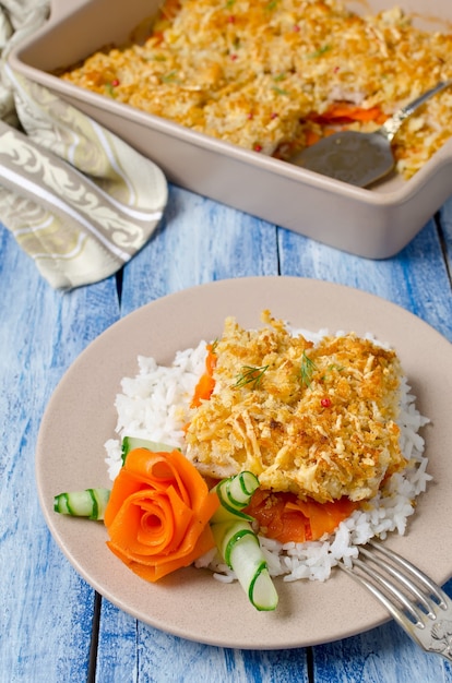 Oven-roasted fish fillet with carrots under a bread crust. For garnish white rice