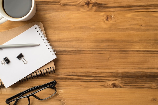 Above overhead close up flat lay view photo of mug of beverage stack of craft notepads eyeglasses isolated loft brown backdrop