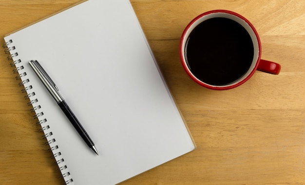 Overhead of notebook with pen and coffee