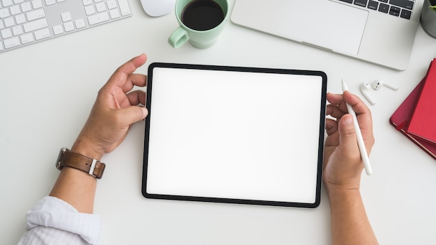 Overhead shot of Businessman working on tablet in workspace with computer, laptop and other office supplies