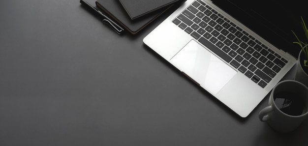 Overhead shot of dark stylish workspace with laptop computer black notebook on black table