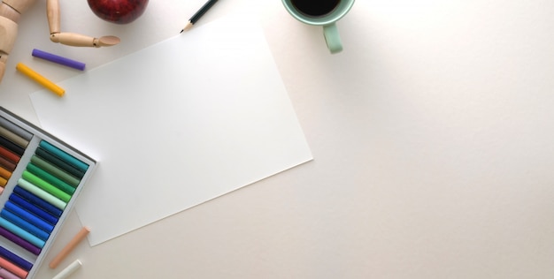 Overhead shot of modern artist workplace with sketch paper and painting tools on white table