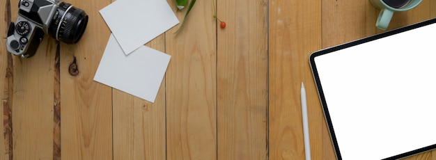 Overhead shot of modern rustic worktable with  tablet, notepad, camera and copy space