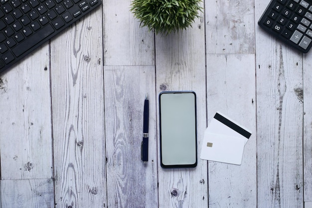 Overhead shot of smart phone credit card and pen on table