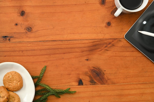 Overhead shot a wooden desk with copy space a plate of cookies a cup of coffee and accessories